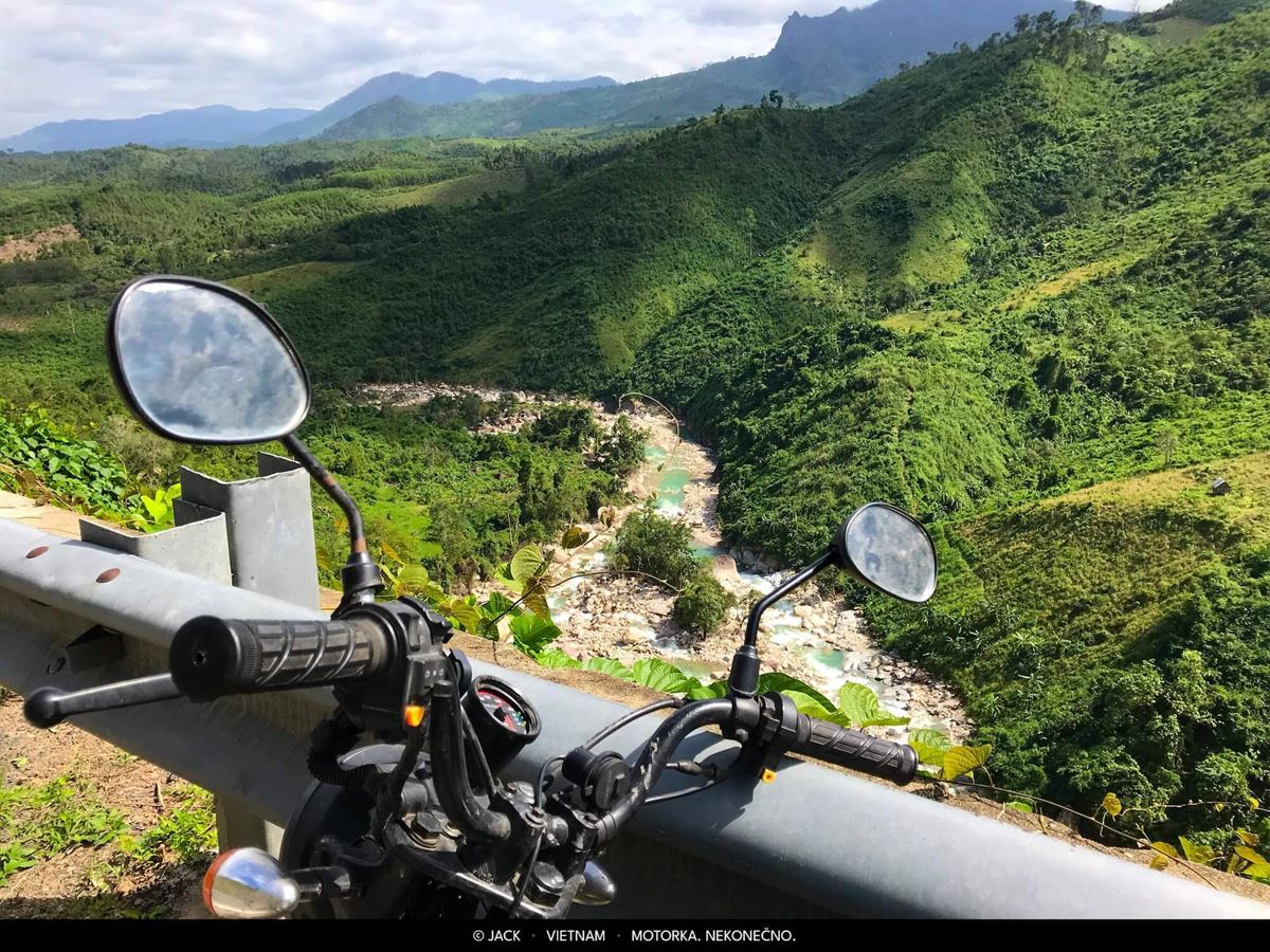 Pohled přes zrcátka motorky na říční údolí ve Vietnamu